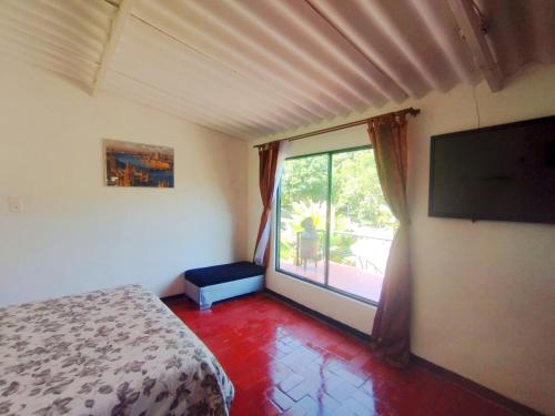 a bedroom with a bed and a large window at Villa tata Granja autosostenible in Sasaima