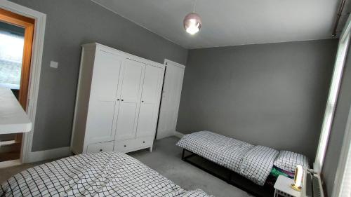 a bedroom with two beds and a white cabinet at Comfortable Home Away From Home in Gillingham