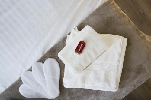 un lit avec une serviette, une enveloppe et une paire de chaussures dans l'établissement L'ADREÏA Confortable T2 - Rénové - Lumineux - Calme - Parking - proche Lille & Tramway, à Marcq-en-Barœul