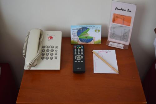 a desk with a remote control and a telephone at Jambura Inn in Gorontalo