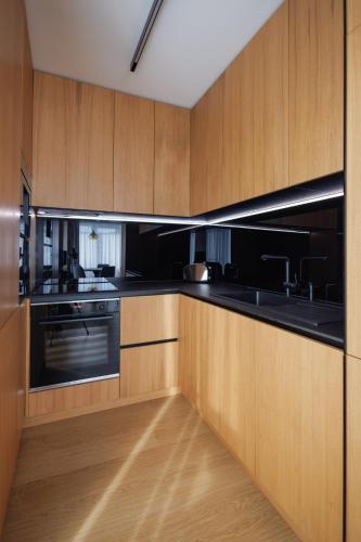 a kitchen with wooden cabinets and black appliances at Moldovei 2 Apartments by Central Park in Cluj-Napoca