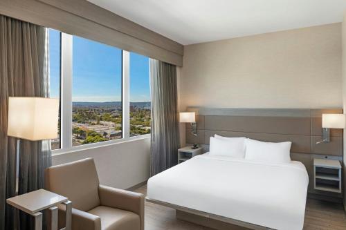 a bedroom with a bed and a chair and a window at AC Hotel by Marriott Beverly Hills in Los Angeles