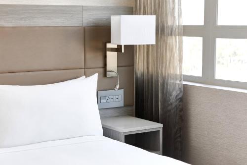 a bedroom with a bed and a lamp next to a window at AC Hotel by Marriott Beverly Hills in Los Angeles