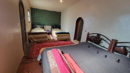 a bedroom with two beds and a green wall at Mhamid camp happy night in Mhamid