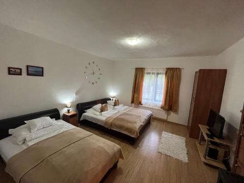 a bedroom with two beds and a clock on the wall at Francesco Apartmanház in Velence