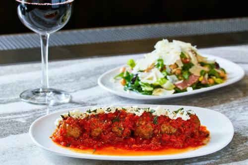 a table with two plates of food and a glass of wine at AC Hotel by Marriott Beverly Hills in Los Angeles