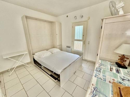 Cette chambre blanche comprend un lit. dans l'établissement Appartement confortable à Aiguebelle avec terrasse et parking privé - FR-1-816-13, au Lavandou