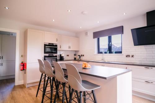 a kitchen with white cabinets and a table with stools at Lowwood Lodges in Houston