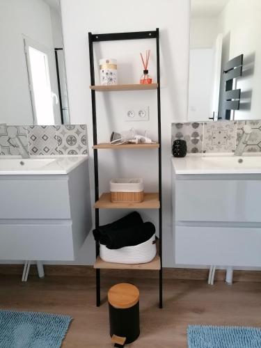 La salle de bains est pourvue de 2 lavabos et d'une étagère avec des serviettes. dans l'établissement campagne chaleureuse, à Béruges