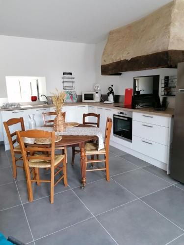 une cuisine avec une table et des chaises dans une cuisine dans l'établissement campagne chaleureuse, à Béruges