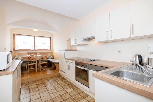 a kitchen with white cabinets and a sink and a table at Aparthotel Landhaus St. Joseph (Indoor Pool) in Mayrhofen