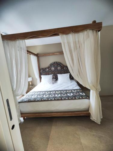 a bedroom with a canopy bed with white sheets and pillows at Logis Hôtel Restaurant La Vraine in Gironcourt-sur-Vraine