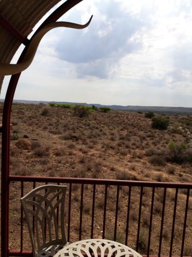 a table and chairs on a porch with a view of the desert at Dopper Joris Bruidswa Adam se Uitspanning in Orania