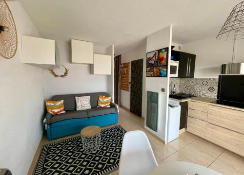 a small living room with a couch and a kitchen at Appartement Cosy, au pied de la plage du Grazel. in Gruissan