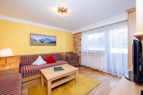 a living room with a couch and a tv at Aparthotel Landhaus St. Joseph (Indoor Pool) in Mayrhofen