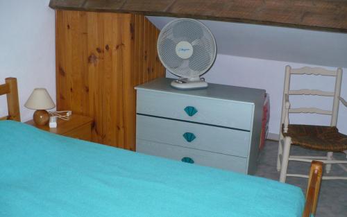 - une chambre avec un lit et un ventilateur sur une commode dans l'établissement Gite olivier a gassin, à Gassin