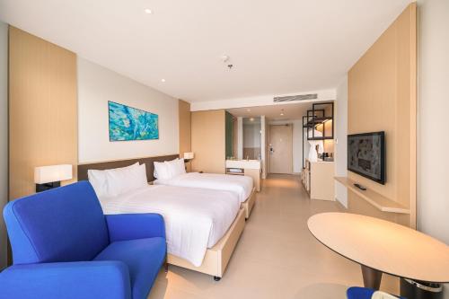 a hotel room with a large bed and a blue chair at Arena Cam Ranh Pearl Bay in Cam Ranh