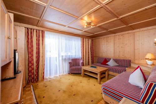 a living room with couches and a table and a television at Aparthotel Landhaus St. Joseph (Indoor Pool) in Mayrhofen