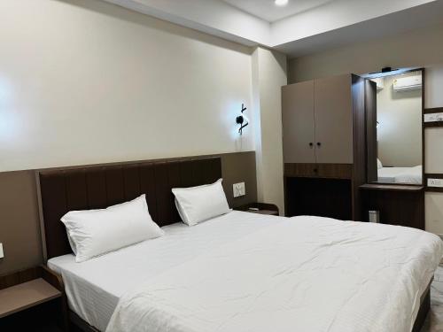 a bedroom with a large white bed with two pillows at Hotel Fun n Food in Bhuj