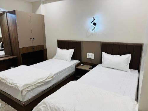 two beds in a room with white sheets at Hotel Fun n Food in Bhuj