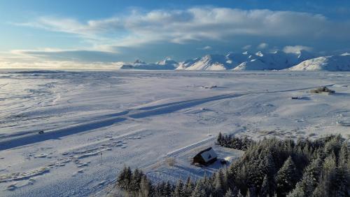 an aerial view of a snow covered field with mountains at Lodge Borgarbrekka in Lón South East of Iceland - Birta Rentals in Höfn
