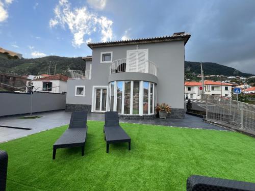 een huis met een gazon met twee stoelen erop bij Villa Machico Valley Flat 2 in Machico