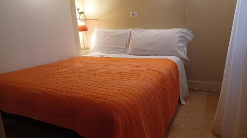 a bed with an orange blanket and white pillows at All'Opera Prima in Verona