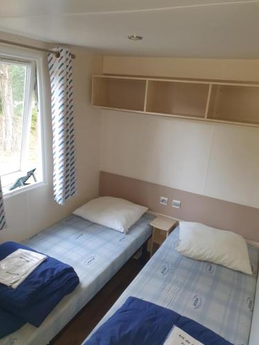 deux lits dans une petite pièce avec une fenêtre dans l'établissement Mobil home 6 personnes, à Barrême