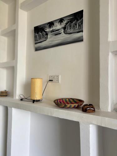a shelf with a lamp and a bowl on it at Samia House in Jambiani