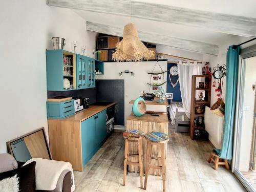 une cuisine avec des placards bleus, une table et des tabourets dans l'établissement Jolie petite villa au coeur des Capellans Piscine, à Saint Cyprien Plage