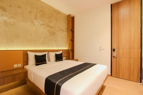 a bedroom with a large white bed with black pillows at Keenan Living Perumnas in Yogyakarta