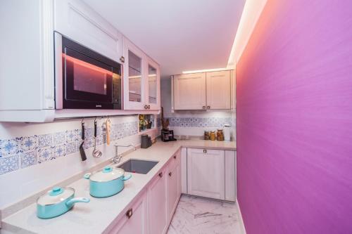 a kitchen with white cabinets and a purple wall at Hotel Madera Hollywood in Hong Kong