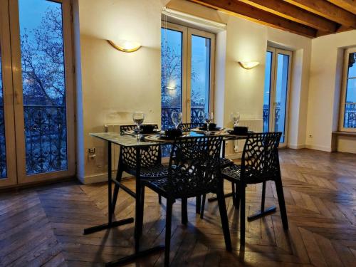 une salle à manger avec une table, des chaises et des fenêtres dans l'établissement Grand loft bourgeois, Coeur Vieux Lyon, à Lyon