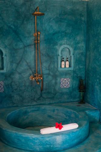 a blue bathroom with a tub with a red flower on it at Casa Paradis Boutique Hotel in Jambiani