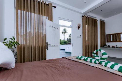 a bedroom with a large bed with a large window at Madiha Ceylon Hotel in Matara