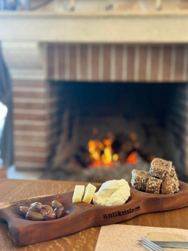 a wooden plate with cheese and nuts and a fireplace at Dictamus Homes in Magoulás