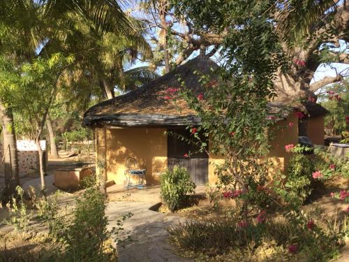 a small house with a yard with flowers at Campement Courbine in Ndangane