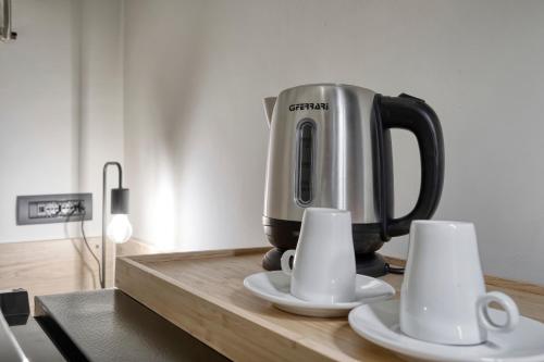 una macchinetta del caffè seduta su un bancone con due tazze di Design Loft in Centro Storico - Casa Courrier a Bologna