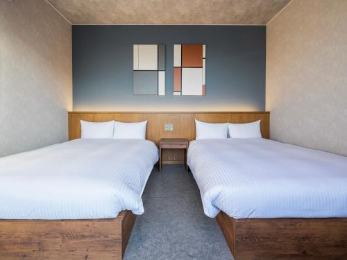 two beds sitting next to each other in a room at LACER OKINAWA NAHA Miebashi in Naha