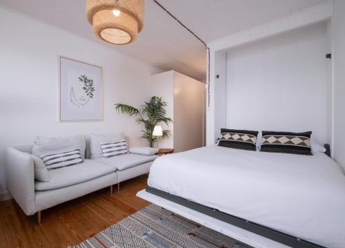 Un dormitorio blanco con una cama y un sofá. en Ocean View Retreat 1, en São Roque