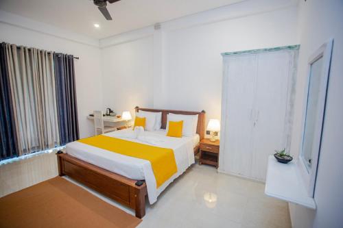 a bedroom with a bed with yellow and white sheets at Monarcho Villa in Talpe