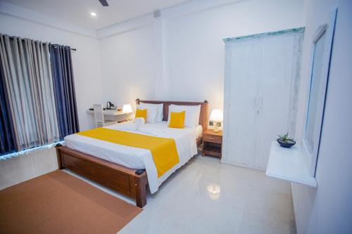 a bedroom with a bed with yellow and white sheets at Monarcho Villa in Talpe