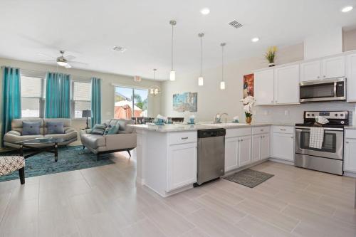a kitchen with white cabinets and a living room at Four Bedroom w/ GameRoom 5152A in Kissimmee