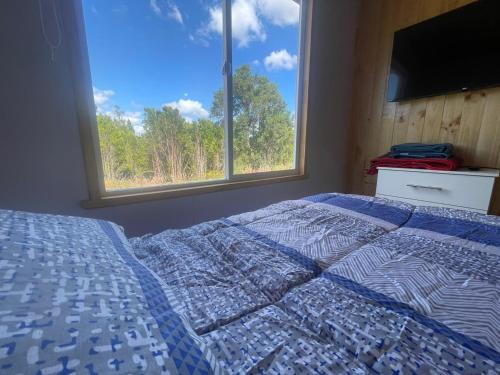 a bedroom with a bed and a large window at Cabañas Aurora Castro Quilquico Chiloé in Yutuy