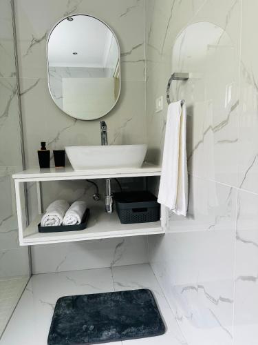 a white bathroom with a sink and a mirror at Sweet Daisies Apartment in Mbabane