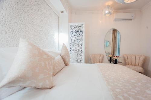 ein Schlafzimmer mit einem weißen Bett, Kissen und einem Spiegel in der Unterkunft Riad Andallaspa in Marrakesch