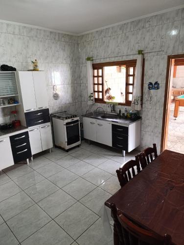 a kitchen with white appliances and a table and a table and chairs at Chácara dos Cunha - Atibaia in Atibaia