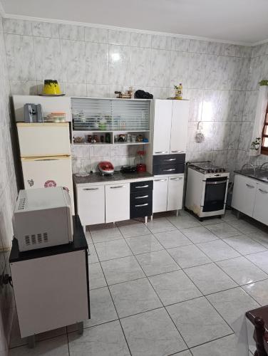 a large kitchen with white cabinets and appliances at Chácara dos Cunha - Atibaia in Atibaia