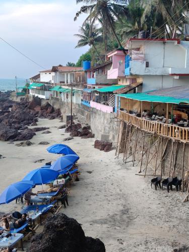 a beach with blue umbrellas and people on the beach at Om Ganesh Guest House Cliffside in Arambol
