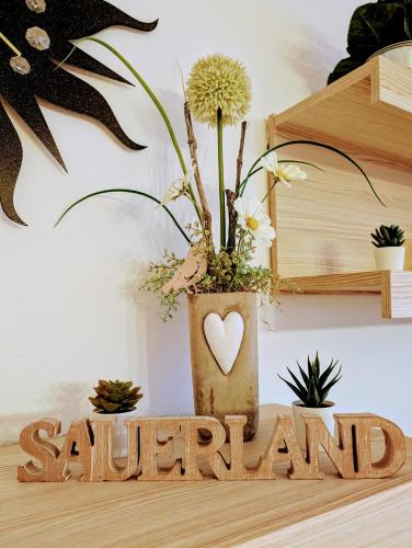 a wooden sign with a vase with a plant at Ferienwohnung Jansen in Kirchhundem